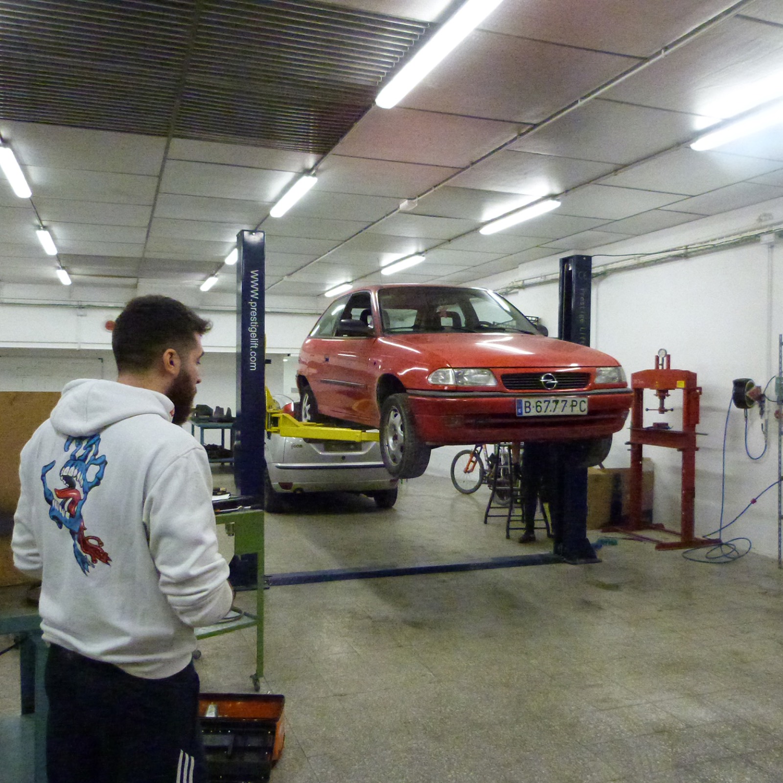 Alumnat al taller d’automoció de l’INS Llobregat, amb un vehicle elevat